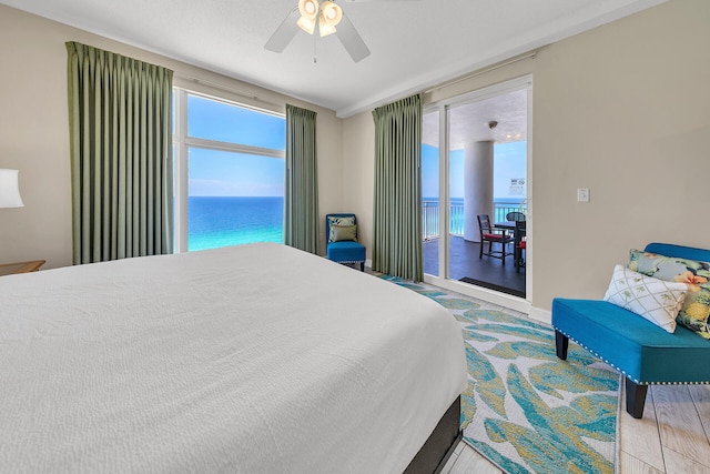 bedroom featuring access to outside, ceiling fan, a water view, and light hardwood / wood-style floors