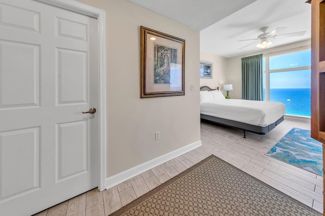 bedroom with ceiling fan, a water view, and a textured ceiling