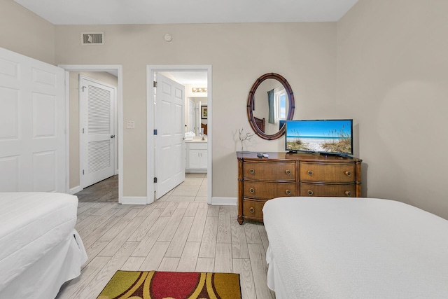 bedroom featuring ensuite bathroom and light hardwood / wood-style flooring