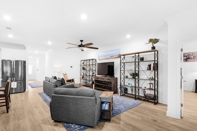 living room with ceiling fan, ornamental molding, and light hardwood / wood-style flooring