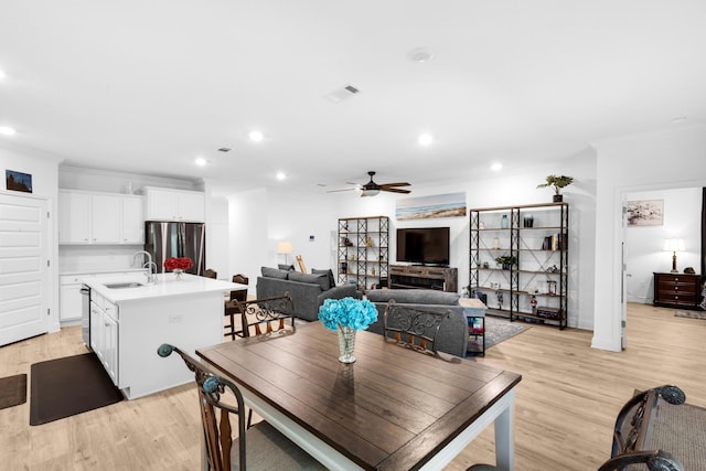 dining room with ceiling fan, light hardwood / wood-style floors, ornamental molding, and sink