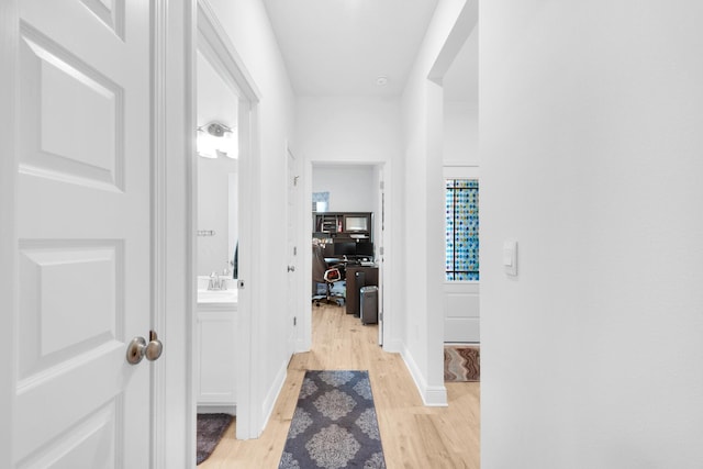 corridor featuring sink and light wood-type flooring