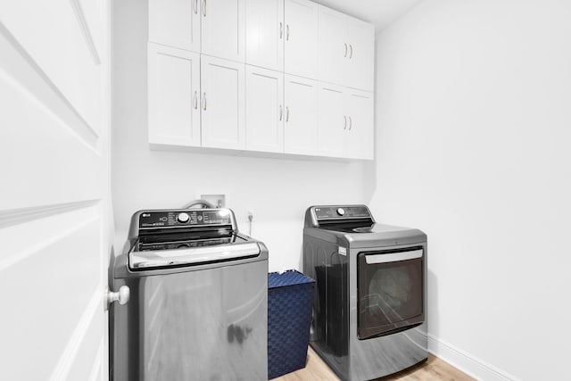 washroom featuring cabinets, separate washer and dryer, and light hardwood / wood-style flooring