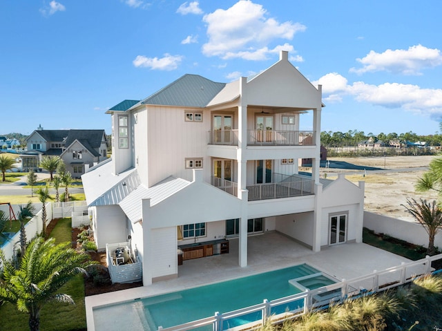 rear view of property with a fenced in pool, a balcony, and a patio