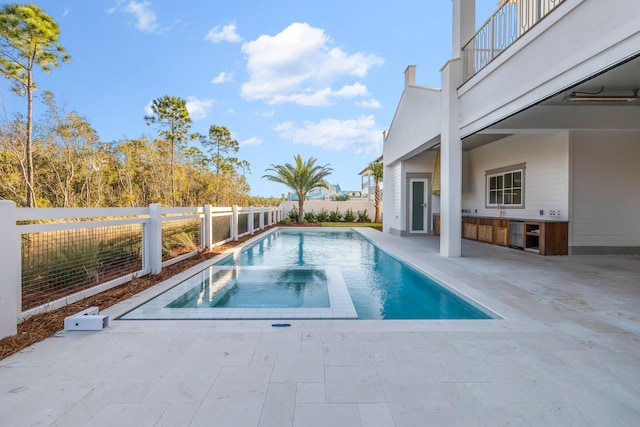 view of pool with an in ground hot tub, exterior kitchen, and a patio