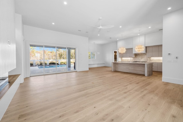 unfurnished living room featuring ceiling fan and light wood-type flooring