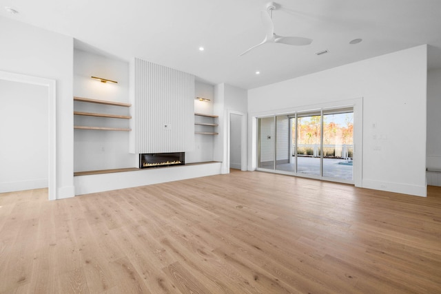 unfurnished living room featuring ceiling fan, a large fireplace, and light hardwood / wood-style floors