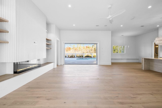 unfurnished living room with ceiling fan and light wood-type flooring