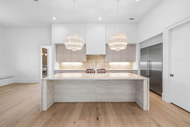 kitchen with pendant lighting, gray cabinetry, a kitchen island with sink, light wood-type flooring, and stainless steel appliances