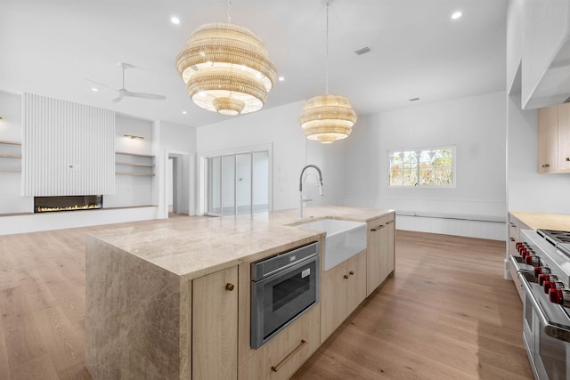 kitchen featuring a large island with sink, sink, stainless steel appliances, and light hardwood / wood-style flooring