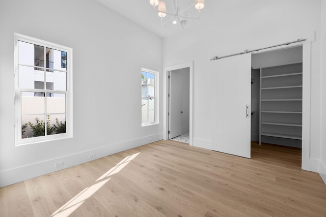 unfurnished bedroom featuring light hardwood / wood-style floors, vaulted ceiling, and a notable chandelier