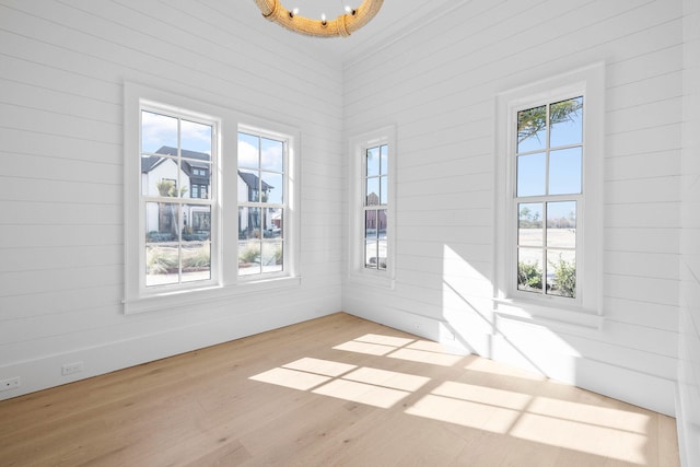 spare room featuring wooden walls and light hardwood / wood-style flooring