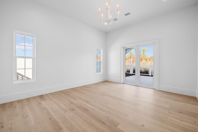 spare room featuring light hardwood / wood-style flooring and an inviting chandelier