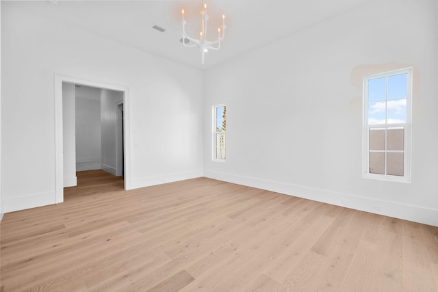 unfurnished room with a notable chandelier and light wood-type flooring