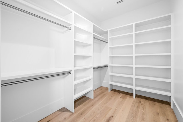 walk in closet with light hardwood / wood-style flooring