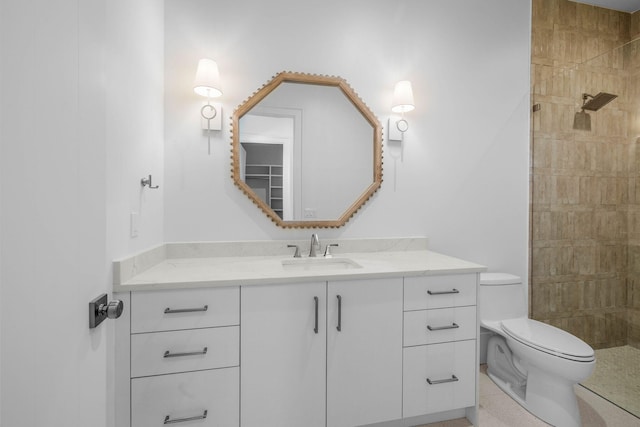 bathroom with a tile shower, vanity, and toilet