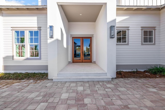 doorway to property featuring stucco siding, board and batten siding, and french doors