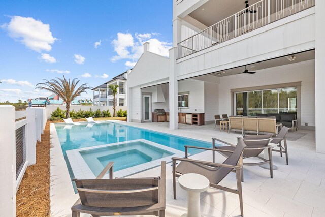 view of swimming pool with a ceiling fan, a patio, a fenced backyard, exterior kitchen, and a pool with connected hot tub