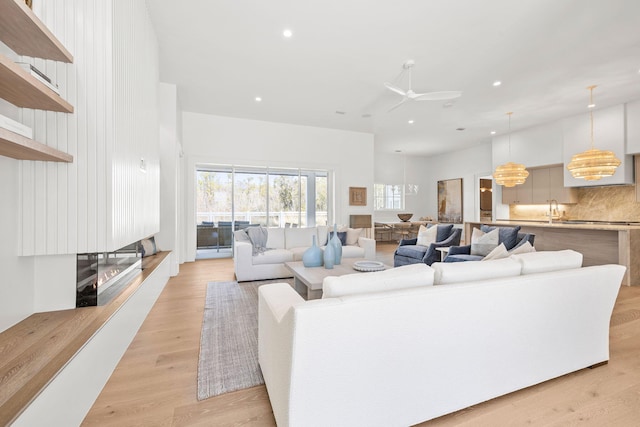 living room featuring light wood-type flooring, ceiling fan, and recessed lighting