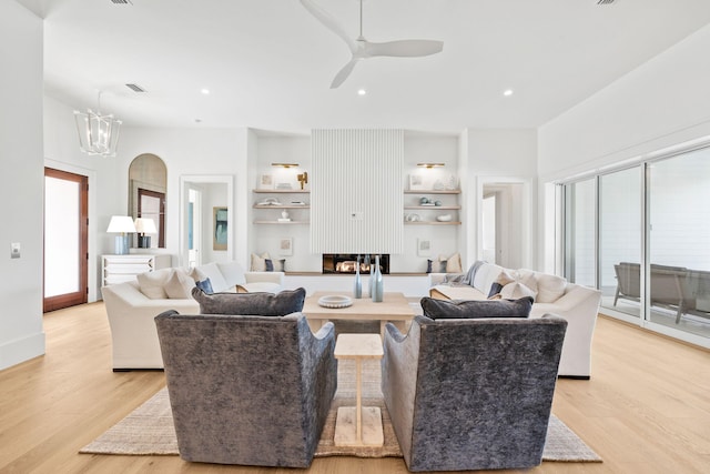 living area with plenty of natural light, ceiling fan with notable chandelier, light wood-type flooring, and recessed lighting