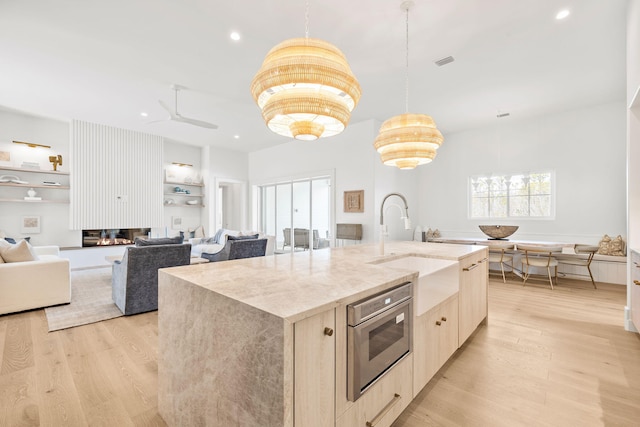 kitchen with light wood-type flooring, visible vents, a sink, and light brown cabinetry