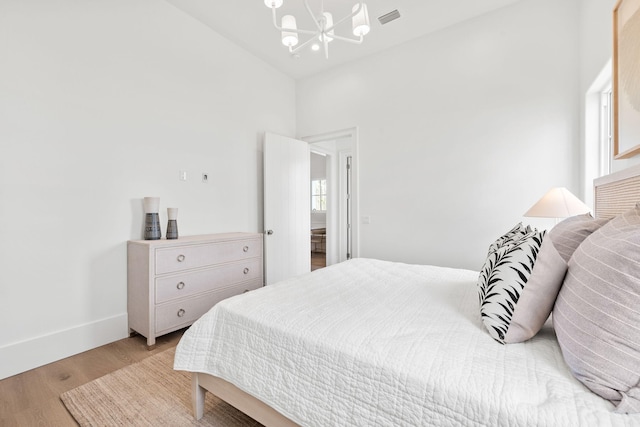 bedroom with visible vents, baseboards, light wood-style flooring, and a notable chandelier