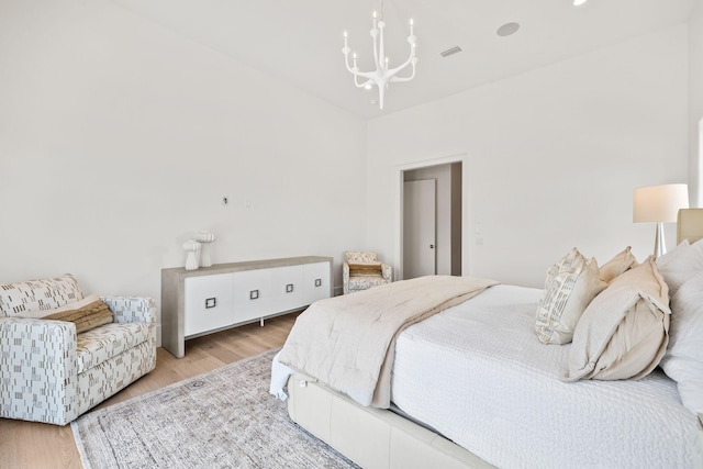 bedroom with a notable chandelier, visible vents, and wood finished floors