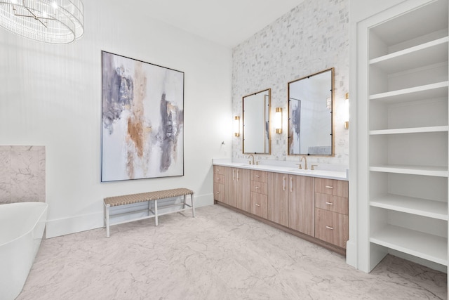 full bath with built in shelves, a sink, marble finish floor, a soaking tub, and double vanity