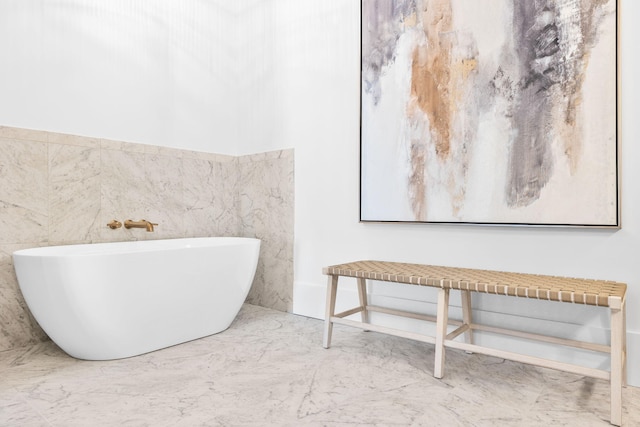 bathroom featuring marble finish floor and a freestanding bath