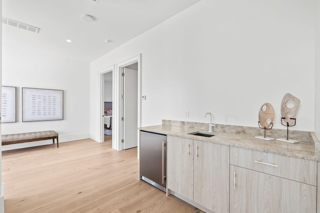 interior space featuring light wood finished floors, baseboards, visible vents, stainless steel refrigerator, and a sink