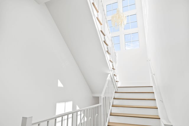 stairs with a towering ceiling and a notable chandelier