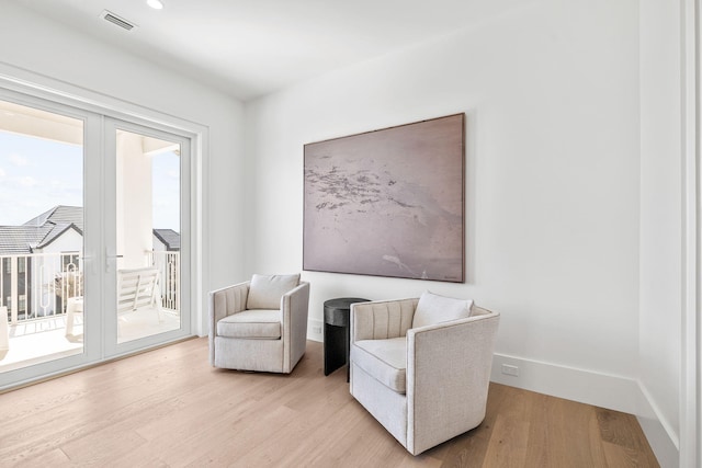 sitting room featuring baseboards, visible vents, and light wood-style floors