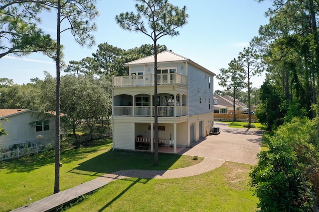 back of property featuring a patio, a balcony, central AC unit, and a lawn