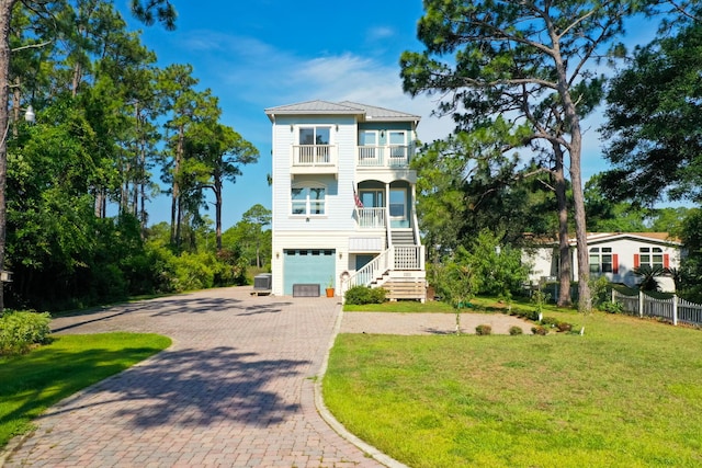 view of front of house featuring a front yard, a balcony, central AC unit, a garage, and a porch