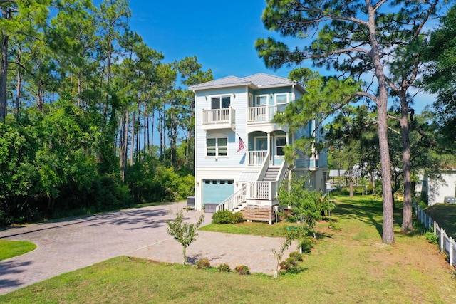 raised beach house featuring covered porch, a garage, and a front yard