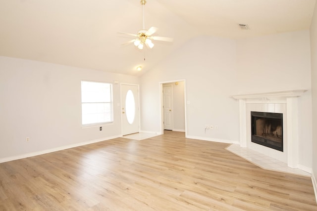 unfurnished living room featuring a tiled fireplace, high vaulted ceiling, light wood-type flooring, and ceiling fan