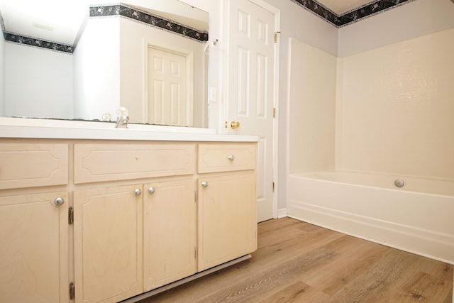 bathroom featuring hardwood / wood-style flooring, vanity, and  shower combination