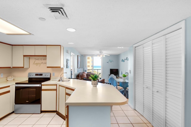 kitchen with light tile patterned flooring, stainless steel electric stove, kitchen peninsula, and cream cabinets