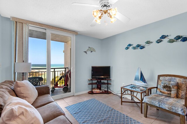 living room with light tile patterned flooring, ceiling fan, and a textured ceiling