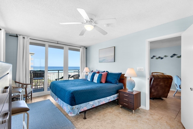 tiled bedroom featuring access to exterior, floor to ceiling windows, a textured ceiling, and a water view