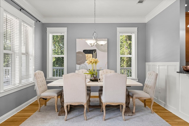 dining room featuring hardwood / wood-style flooring, a healthy amount of sunlight, and ornamental molding