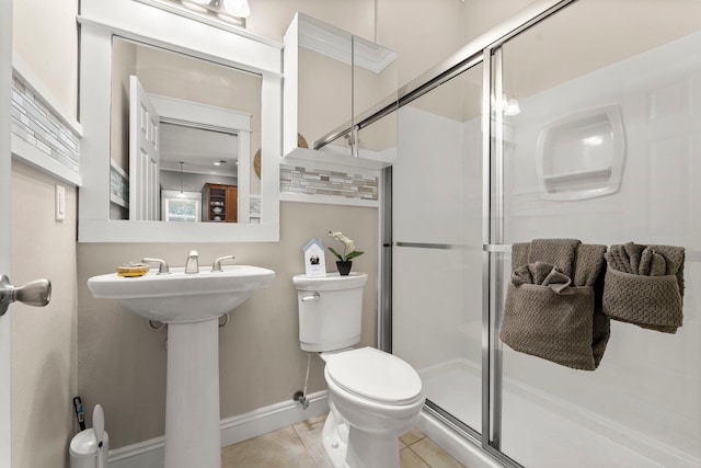 bathroom featuring sink, tile patterned flooring, crown molding, toilet, and a shower with door