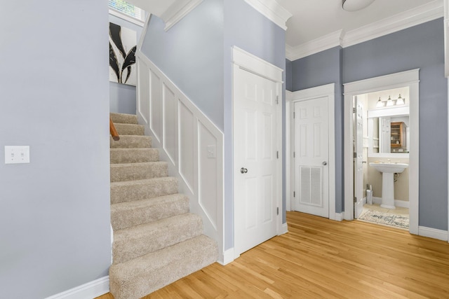 staircase with hardwood / wood-style floors, ornamental molding, and sink