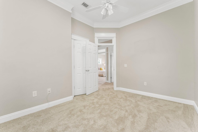 unfurnished bedroom with ceiling fan, crown molding, and light colored carpet