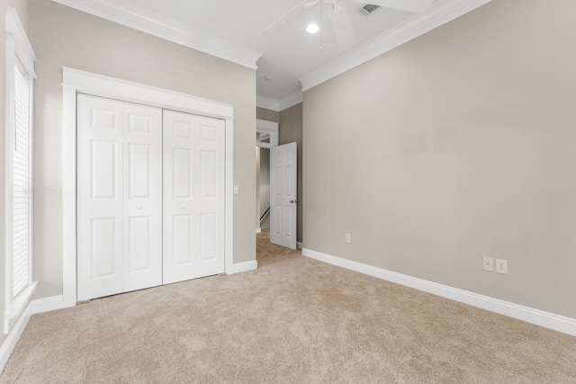 unfurnished bedroom with ceiling fan, ornamental molding, light carpet, and a closet