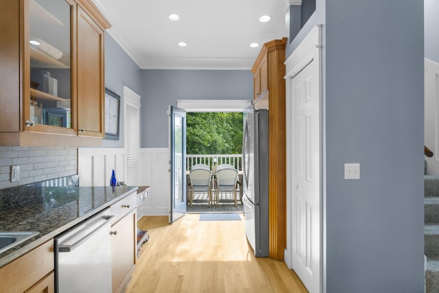 kitchen featuring dark stone counters, crown molding, decorative backsplash, light hardwood / wood-style floors, and stainless steel appliances