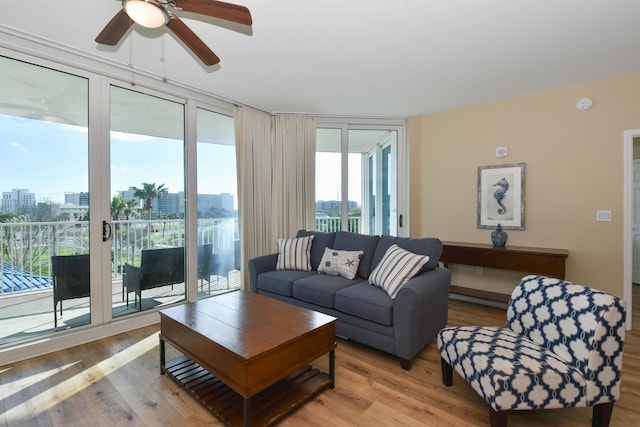 living room featuring ceiling fan, expansive windows, and light hardwood / wood-style flooring