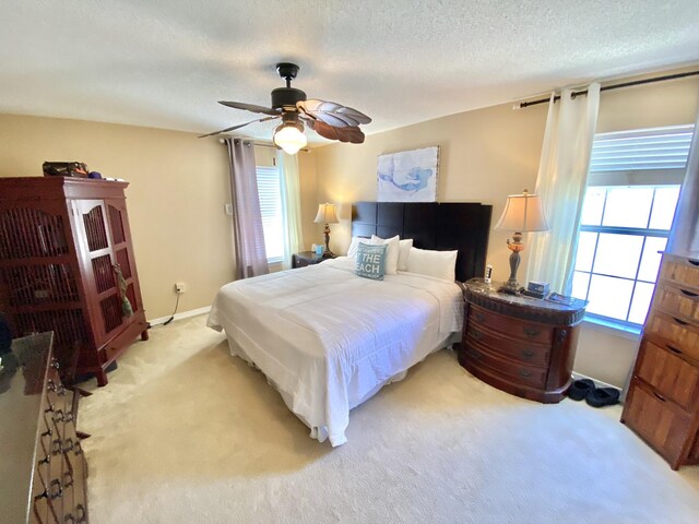 bedroom with multiple windows, ceiling fan, and light colored carpet