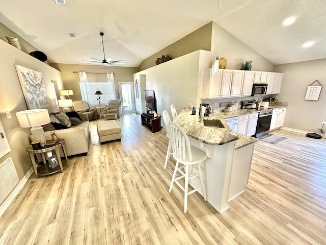 kitchen with a breakfast bar area, appliances with stainless steel finishes, kitchen peninsula, white cabinets, and sink