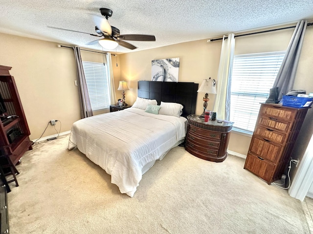 bedroom featuring ceiling fan, light carpet, and a textured ceiling